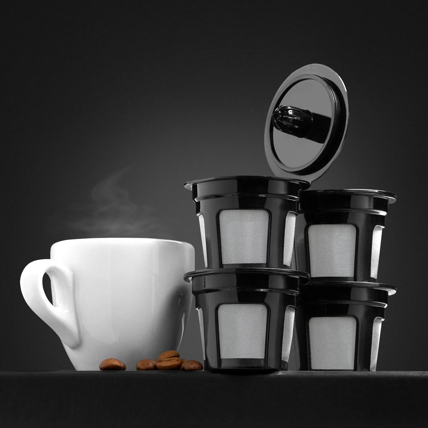 Black reusable K-Cups with a white cup and coffee beans on a dark background