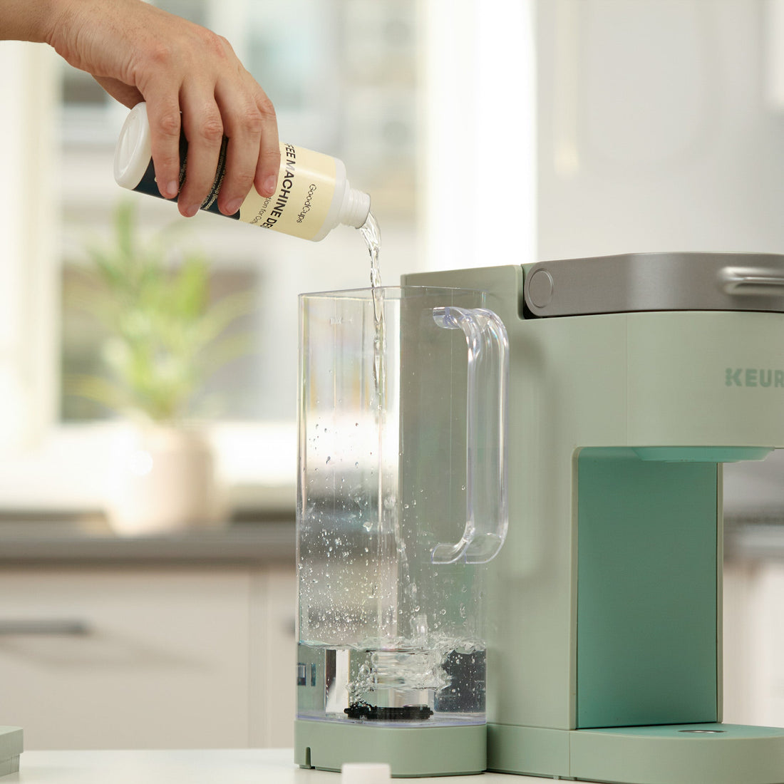 Pouring GoodCups Coffee Machine Descaler into the water reservoir of a green Keurig brewer to begin descaling