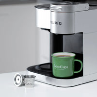 Keurig coffee maker with a green 'GoodCups' mug on a white surface