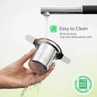 Hand holding a metallic filter under running water with text indicating ease of cleaning and dishwasher safety.