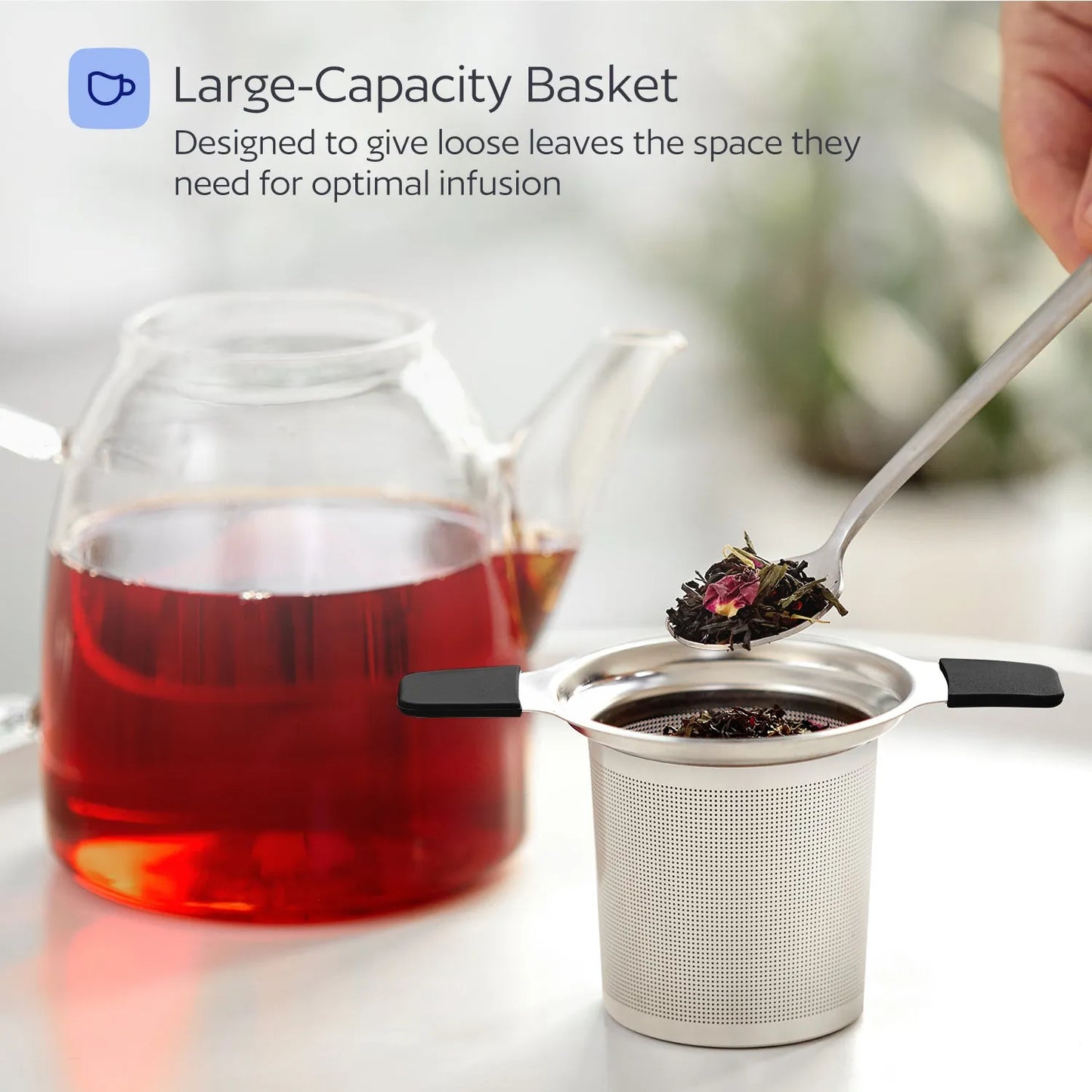 Tea infuser with loose tea leaves next to a teacup of red tea, with text about large-capacity basket.