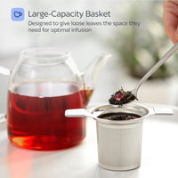 Tea infuser with loose tea leaves next to a teacup of red tea.