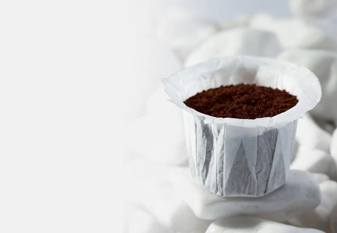 Paper coffee filter with ground coffee on a white background