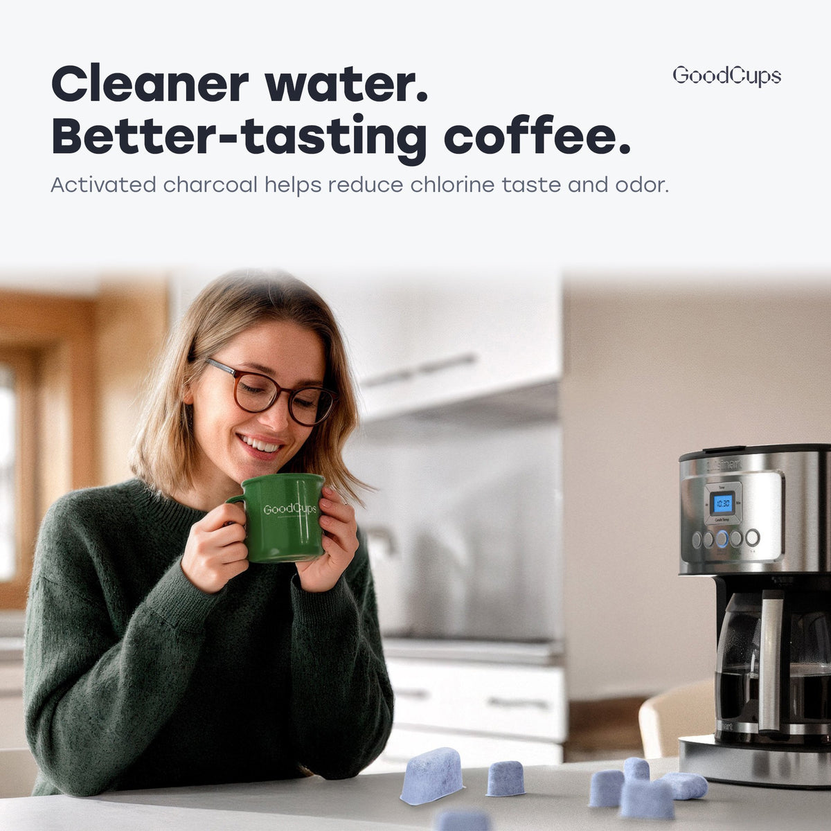 Woman enjoying coffee from a GoodCups mug next to a Cuisinart coffee maker and charcoal water filters