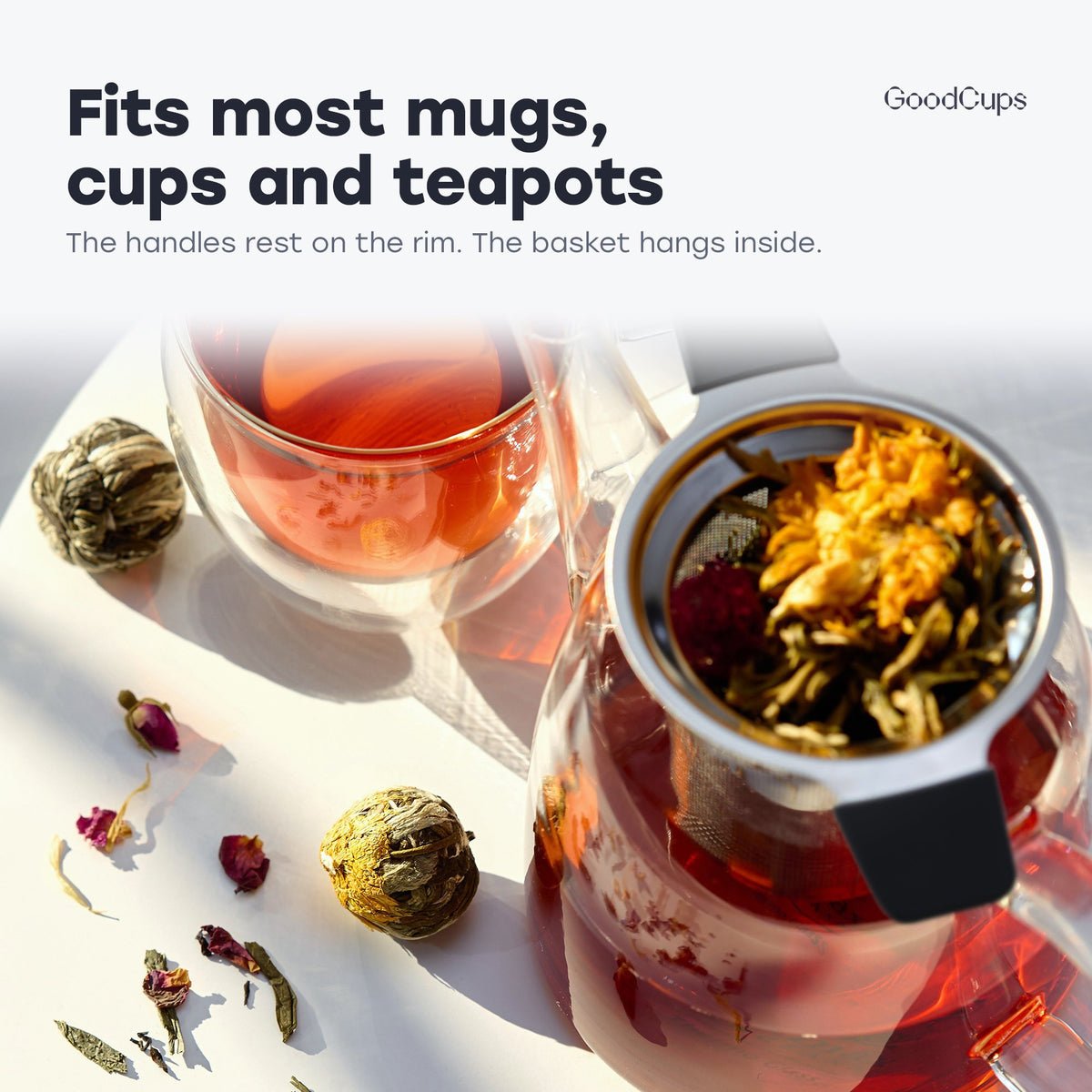 Tea infuser with black handles resting in a glass teapot: fits most mugs, cups and teapots