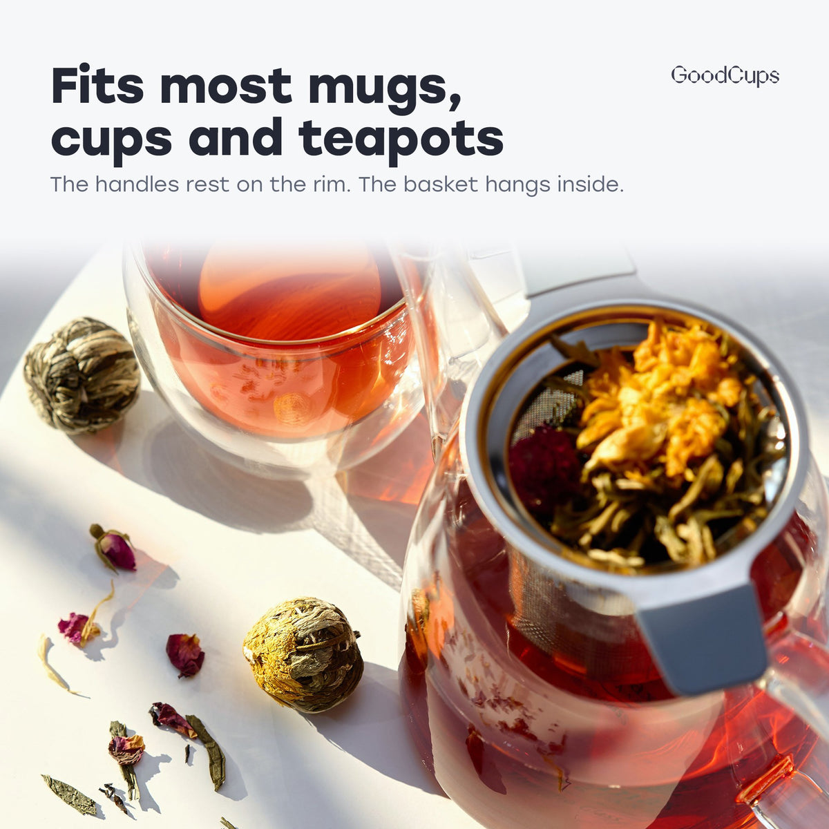 Tea infuser with gray handles resting in a glass teapot: fits most mugs, cups and teapots